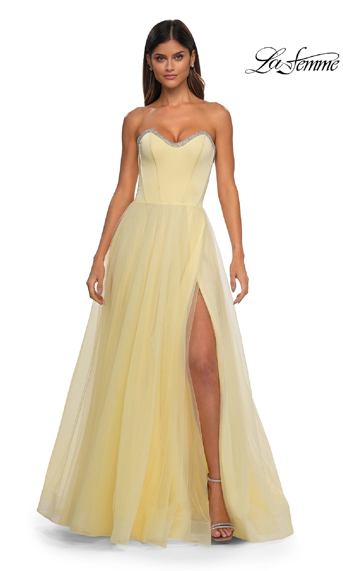 A woman models the La Femme 32731 strapless long prom ball gown in light yellow, featuring a sweetheart neckline, rhinestone trim, tulle skirt, and high slit against a white background.